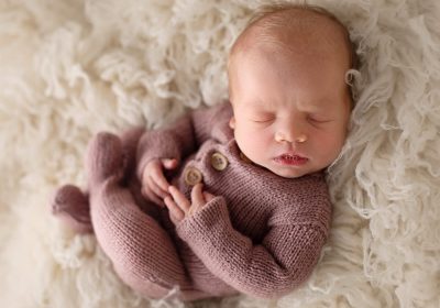 cream flokati with newborn baby in a pink knitted romper photographer